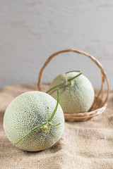 Fresh of whole orange melon or cantaloupe on burlap fabric sack background and wooden table. Favorite fruit in summer concept. . The family of Cucurbitaceae.