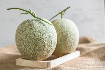 Fresh of whole orange melon or cantaloupe on burlap fabric sack background and wooden table. Favorite fruit in summer concept. . The family of Cucurbitaceae.