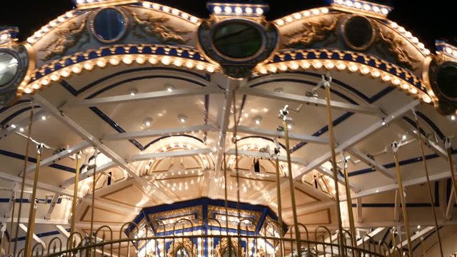 Illuminated merry go round in park. Brightly illuminated roundabout spinning in wonderful amusement park at night.