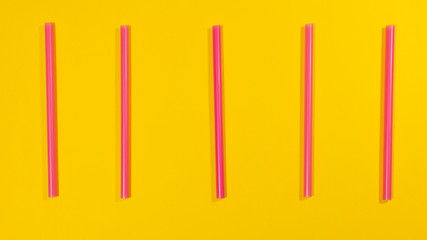 Straws lined up on a yellow surface
