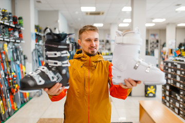 Man shows ski or snowboarding boots in sports shop
