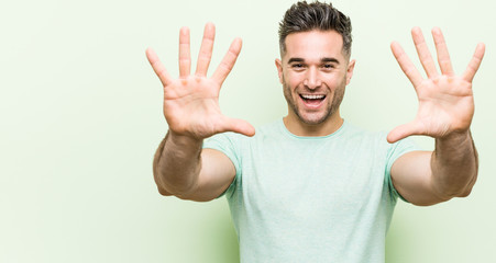 Naklejka premium Young handsome man against a green background showing number ten with hands.