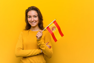 Young european woman holding a spanish flag smiling confident with crossed arms.