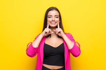 Young woman over isolated yellow background smiling with a happy and pleasant expression