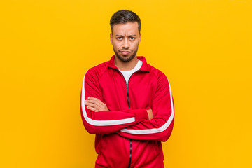 Young filipino fitness man frowning face in displeasure, keeps arms folded.