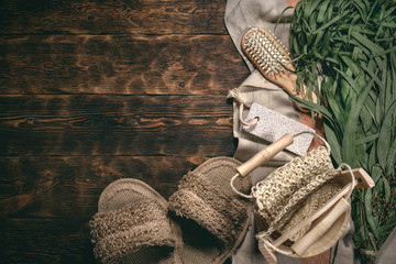Eucalyptus bath broom and other bathhouse accessories on a wooden table flat lay background with copy space.