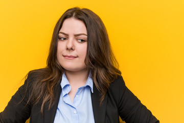 Young plus size caucasian business woman confused, feels doubtful and unsure.