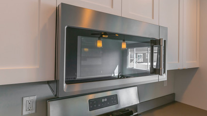 Panorama Close up of the microwave and wooden cabinets mounted on the wall of a kitchen