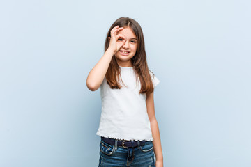 Cute girl excited keeping ok gesture on eye.