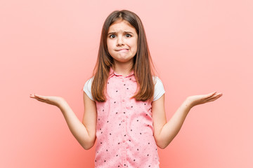 Cute little girl confused and doubtful raising him hands to hold a copy space.
