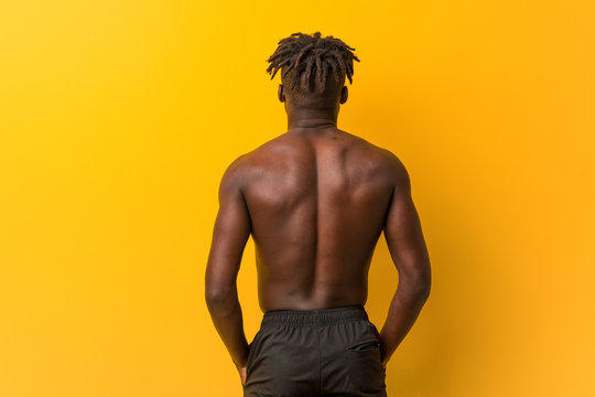 Young Black Man Shirtless Wearing Swimsuit From Behind, Looking Back.