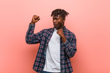 Young african black man raising fist after a victory, winner concept.