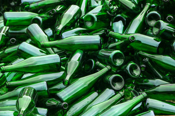 whole and broken green bottles, lie mountain on pavement. Concept: waste recycling, disposal of...