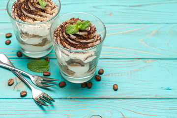 Classic tiramisu dessert in a glass on blue wooden background