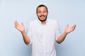 Naklejka premium Colombian man over isolated blue wall smiling a lot