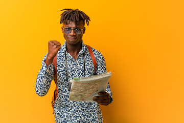 Young rasta black man holding a map showing fist to camera, aggressive facial expression.