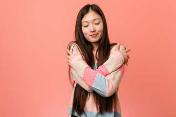 Young cool chinese woman hugs himself, smiling carefree and happy.