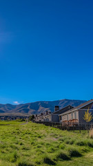 Fototapeta na wymiar Panorama frame Houses on a lush grassy field under the blazing sun and vivid blue sky
