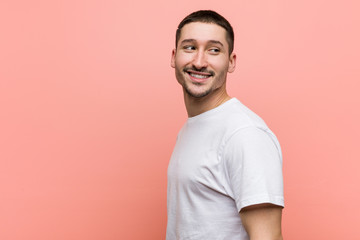 Young casual man looks aside smiling, cheerful and pleasant.