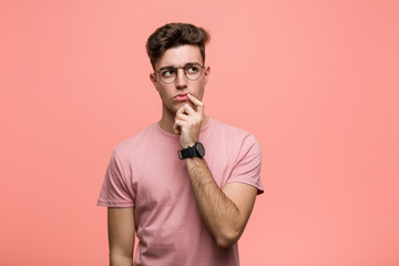 Young cool caucasian man looking sideways with doubtful and skeptical expression.