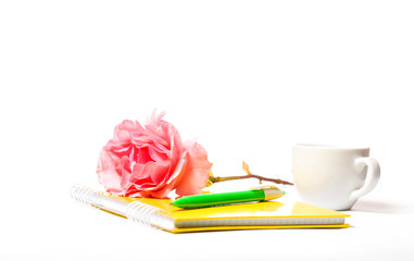 yellow notebook rose and pen on a white background