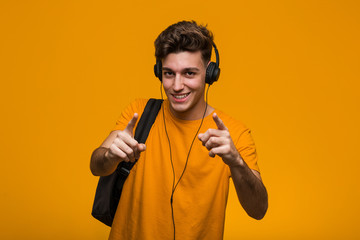 Young cool student man listening to music with headphones shouting excited to front.
