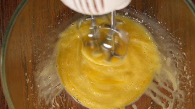 Slow motion crop shot of woman preparing homemade omelette mixing with whisk eggs.