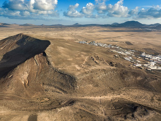 Aerial view of a desert landscape on the island of Lanzarote, Canary Islands, Spain. Mountains of the village of Soo and in the background Timanfaya. Reliefs and volcanoes on the horizon