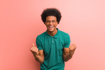 Young african american man over a pink wall surprised and shocked