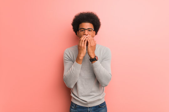Young african american man over a pink wall very scared and afraid hidden