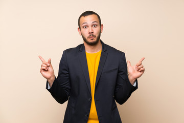 Colombian man over isolated background pointing to the laterals having doubts