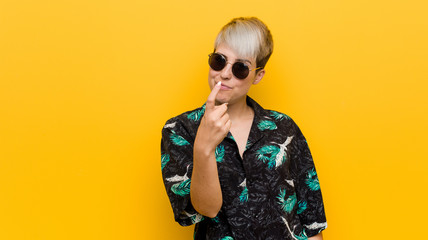 Young curvy woman wearing a summer look pointing with finger at you as if inviting come closer.