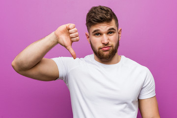 Young handsome caucasian man showing a dislike gesture, thumbs down. Disagreement concept.