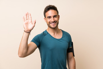 Handsome sport man over isolated background saluting with hand with happy expression © luismolinero