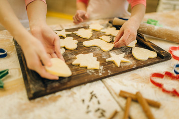 Little girls chefs spread out cookies on board