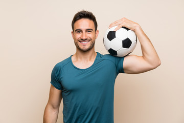 Handsome sport man over isolated background holding a soccer ball