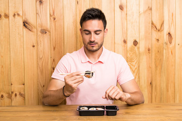 Handsome young man in a kitchen with sushi