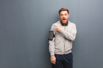 Obraz premium Young fitness redhead man pointing to the side