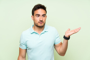 Handsome young man over isolated background making doubts gesture