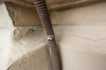 Obraz premium Rusty metal corrugated hose with wire in the corner of the house
