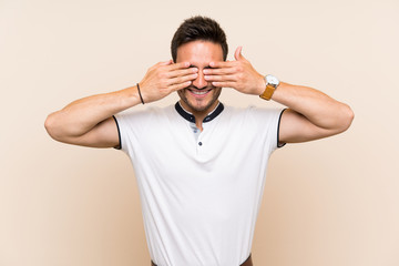 Handsome young man over isolated background covering eyes by hands