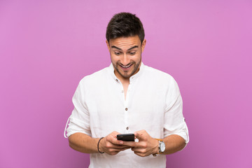 Handsome young man over isolated background surprised and sending a message