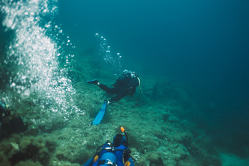 Fototapeta na wymiar Rear view of two scuba divers diving underwater