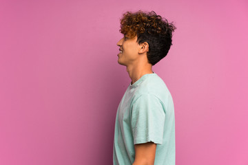 Young african american man over isolated purple wall standing and looking to the side