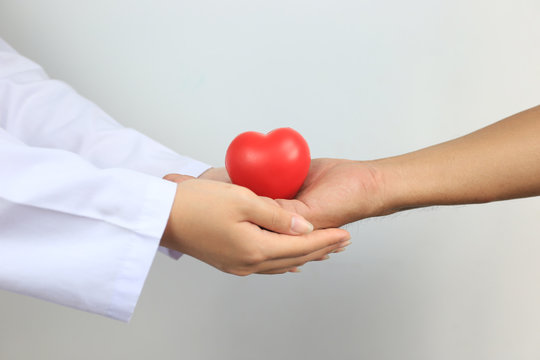 Doctor holding a red heart ball to Senior man on white background, Medicine and Health care concept