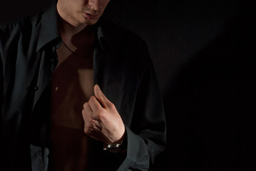A man wears a dark shirt on a naked body. Isolate with copy space on black background. The guy...