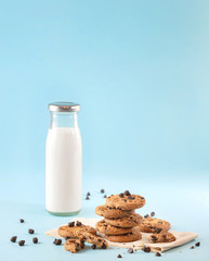 Cookies with chocolate chips and fresh milk bottles on the ground, light blue pastel colors