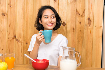 Asian young woman having breakfast holding a cup of coffee