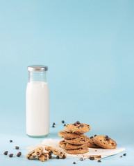 Cookies with chocolate chips and fresh milk bottles on the ground, light blue pastel colors