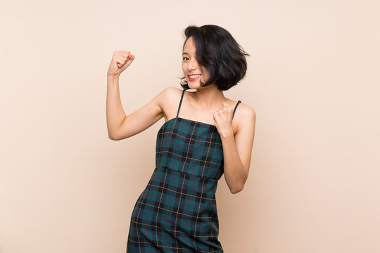 Asian young woman over isolated yellow wall celebrating a victory